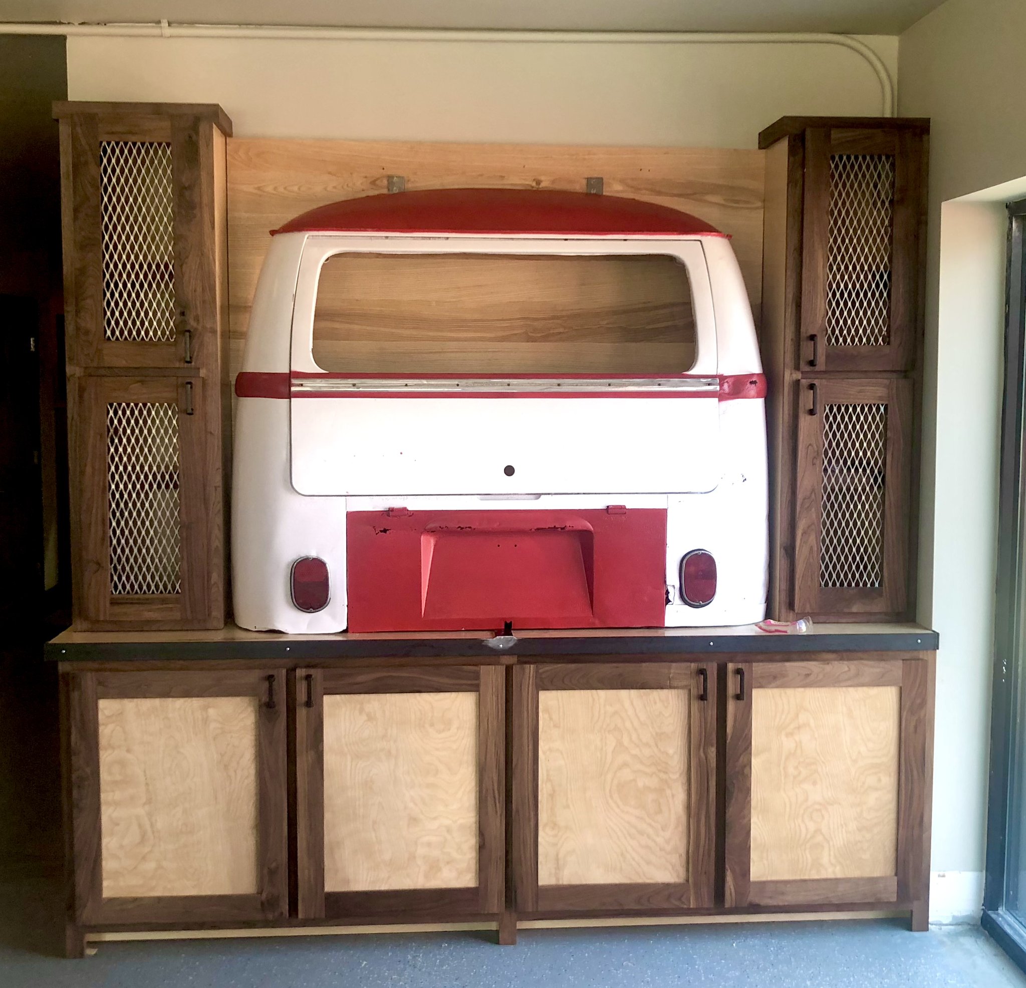 Custom walnut and bird eye maple cabinet built around a VW Bus rear window — unique feature installation