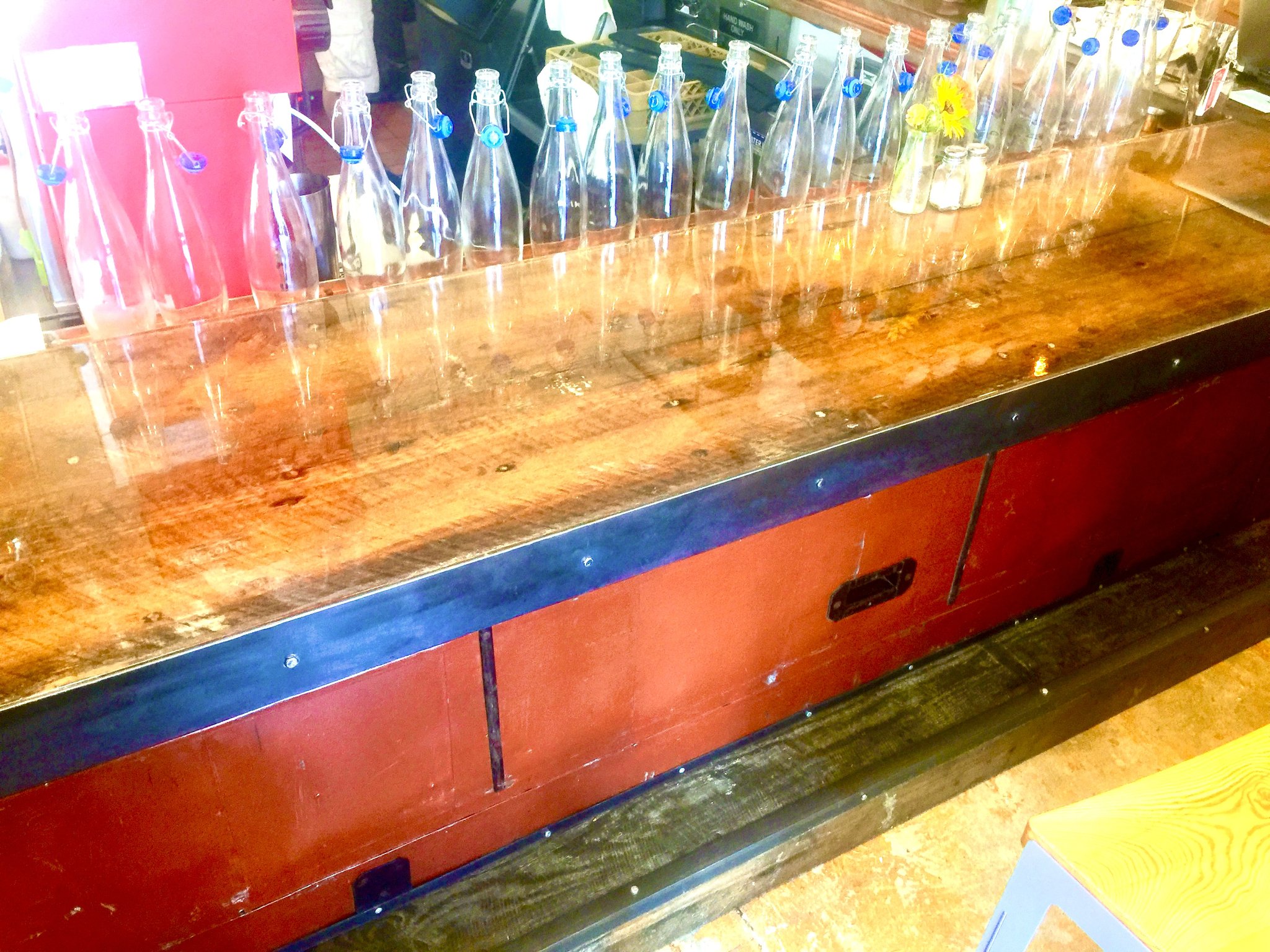 Commercial bar build at Petite Chou — copper epoxy bar top with painted front and brass foot rail