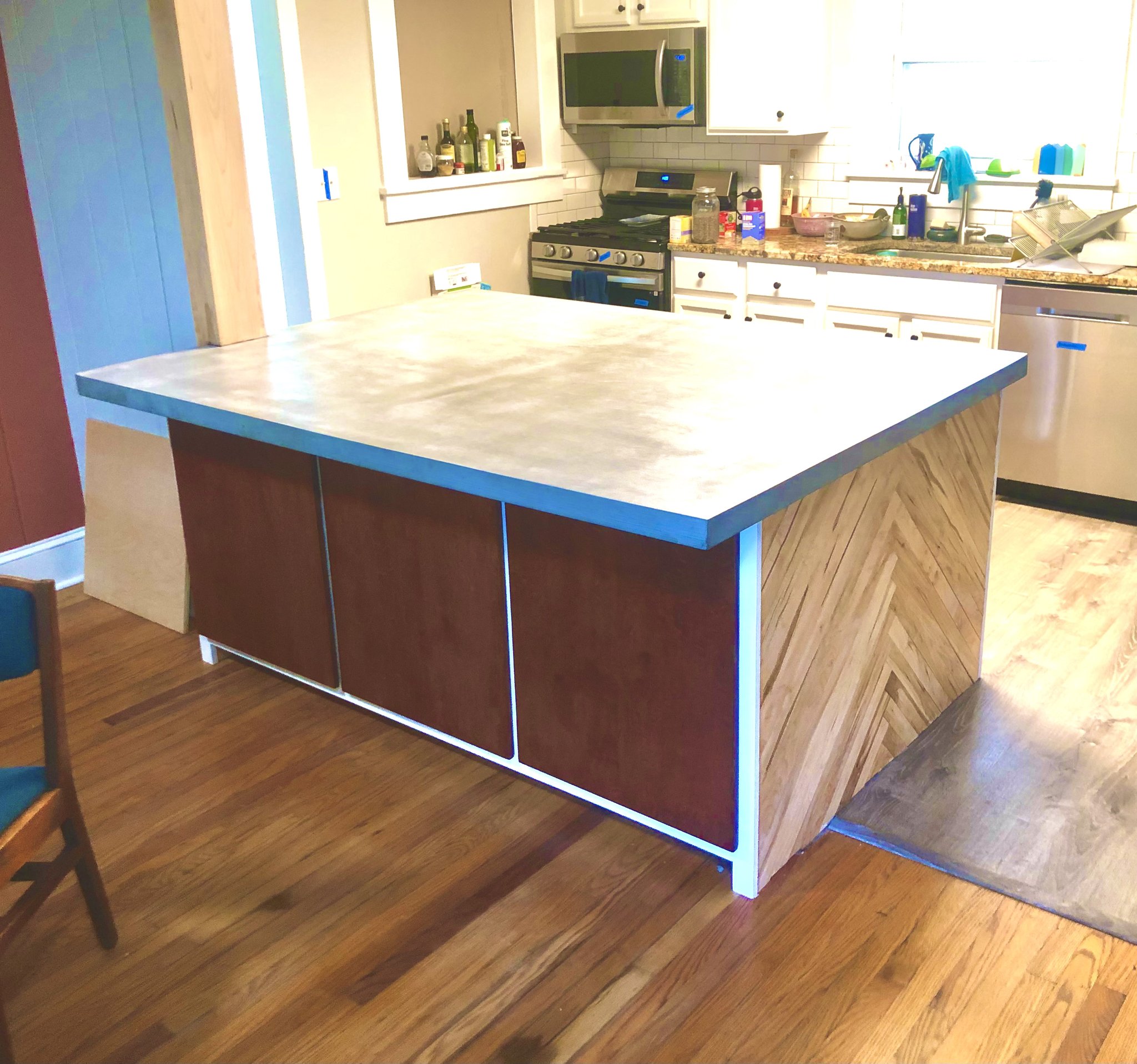 Kitchen island with herringbone wood panel sides and cast concrete countertop