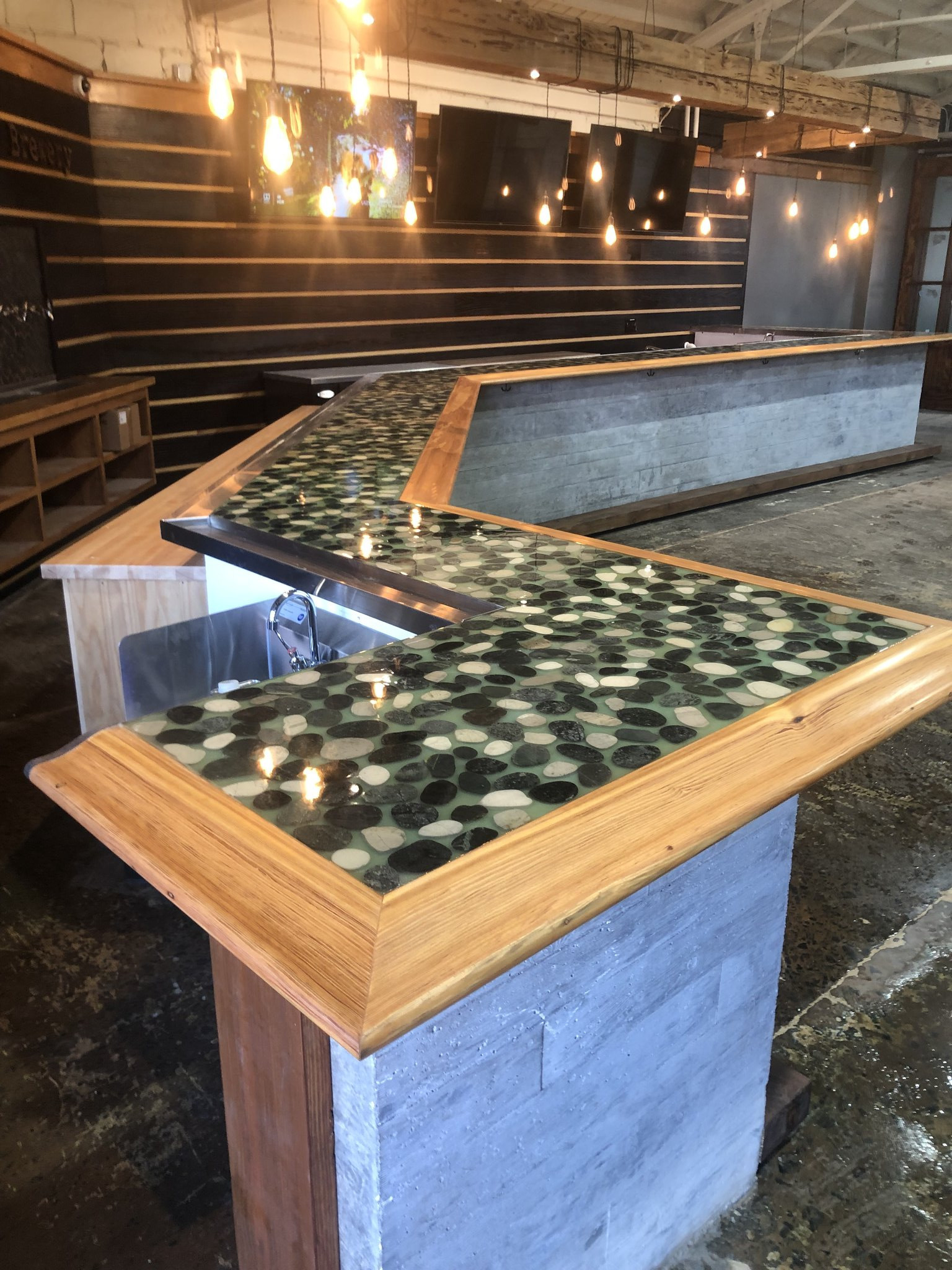 Epoxy and river stone bar top at French Broad River Brewing, Asheville NC — encapsulated stone set in epoxy with hardwood bar frame